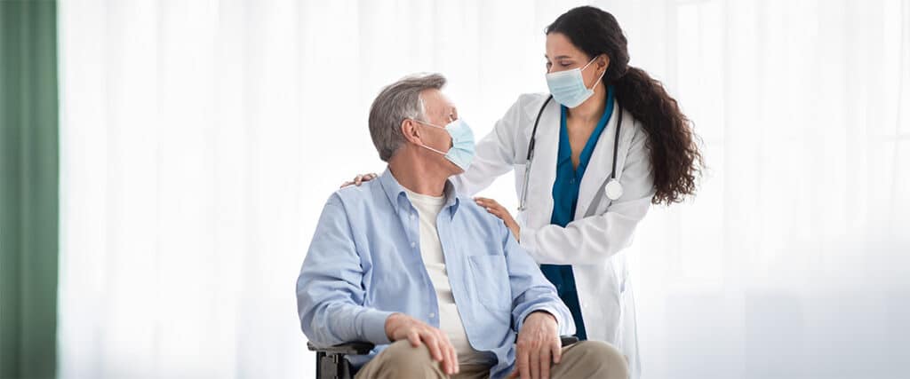 A nurse and patient in masks looking at each other.