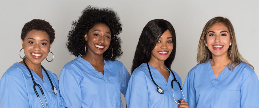 Four smiling women in blue scrubs